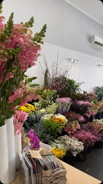 Snapdragons in the foreground and buckets of blooms along the shop wall